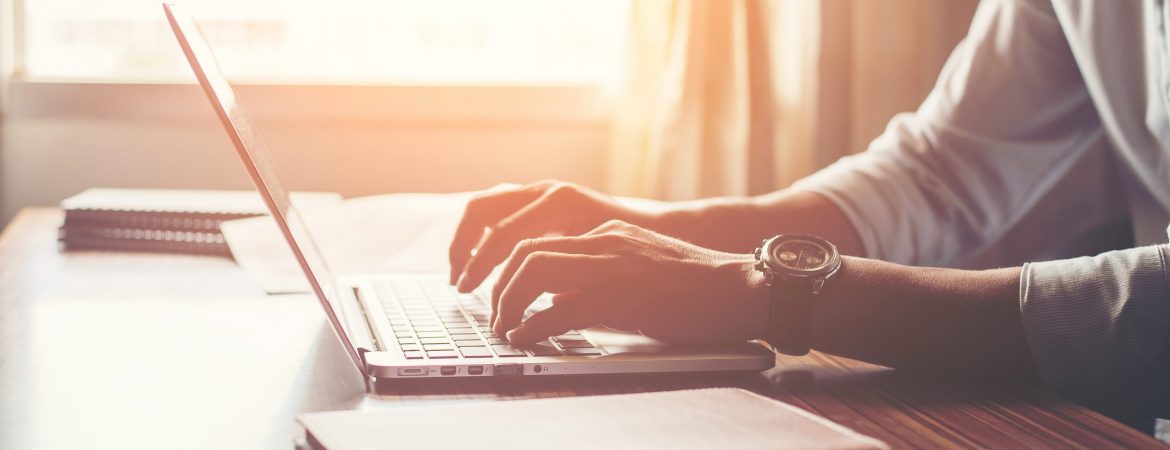 Close-up of male hands using laptop in home.